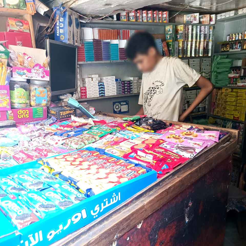 A young boy in Egypt examines snacks next to a cigarette display at his eye-level.